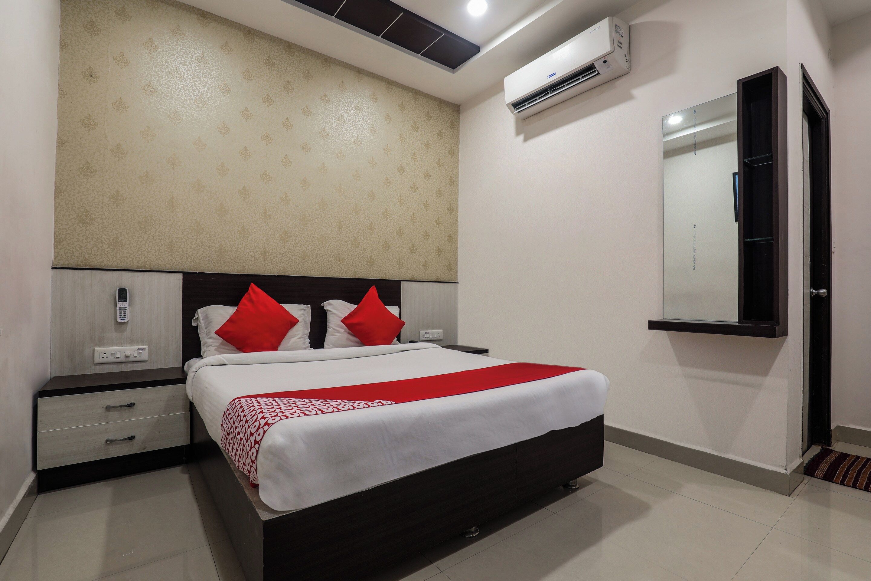Quarto de hotel com cama, mesa de cabeceira e ar condicionado fixado na parede.