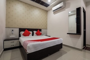 Habitación de hotel con cama, mesita de noche y aire acondicionado de pared.