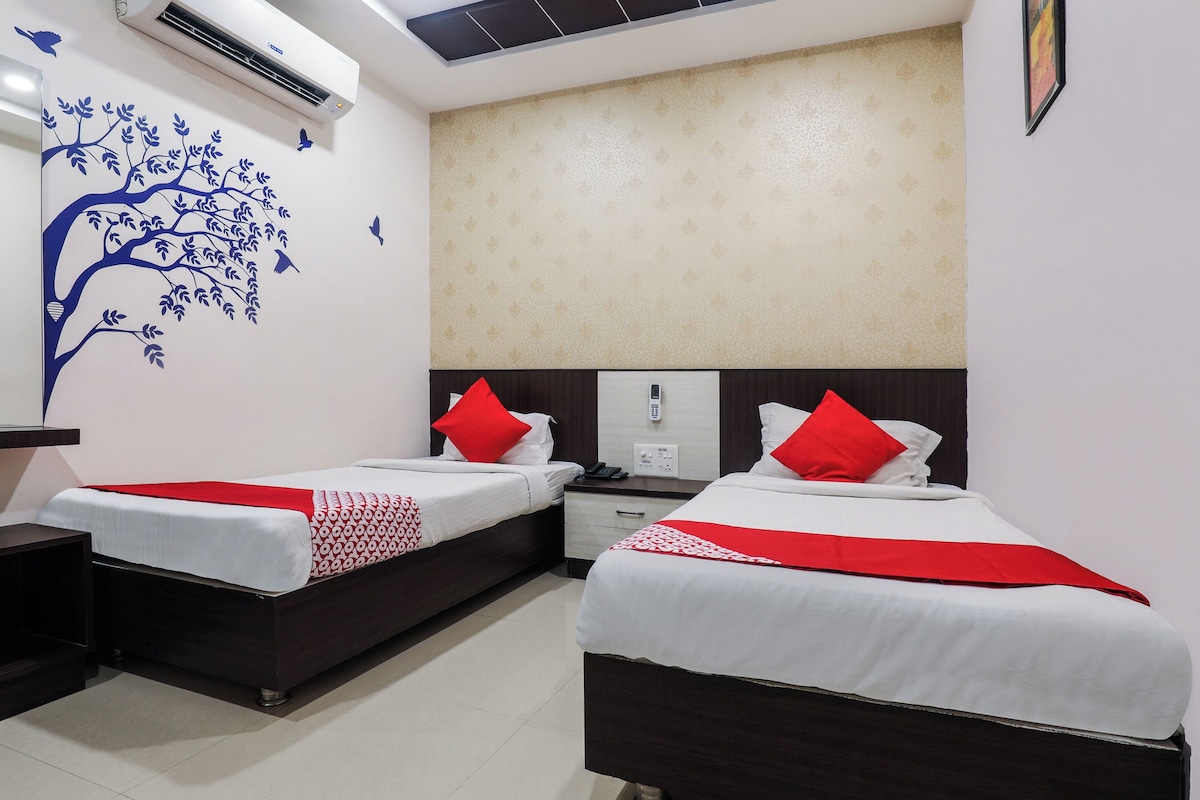 Habitación de hotel con dos camas, aire acondicionado de pared, pared estampada y techo con tragaluz.