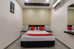 Una habitación de hotel con cama, mesitas de noche, teléfono y aire acondicionado.