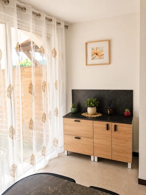 Une cuisine moderne avec un plan de travail noir, des meubles en bois et une plante en pot.