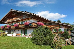 A traditional Alpine-style building with a sloped roof, balconies with flower boxes, and a well-maintained garden. - Apartment in Krün with swimming pool (Krün)