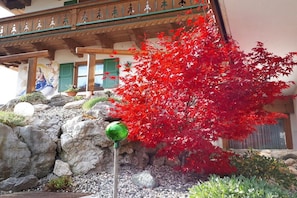 A building with a traditional architectural style, featuring a stone wall and a wooden balcony with a green door. - Apartment in Krün with swimming pool (Krün)