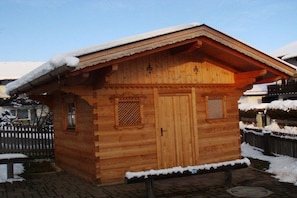 Una cabana de fusta amb teulada inclinada, dues portes i una petita finestra.