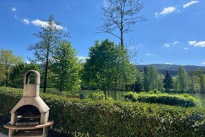 A stone outdoor grill in a park with a lake and trees in the background. - Holiday apartment by the lake with lake view, upper floor (Arrach)