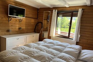 A bedroom with a bed, a TV mounted on the wall, a window with curtains, and a wooden dresser. - Holiday apartment by the lake with lake view, upper floor (Arrach)