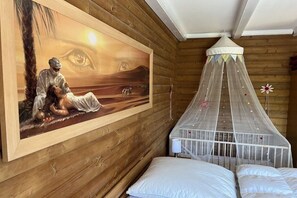 Een kamer met een houten wand, een muurschildering, een hemelbed en een wit ledikant.
