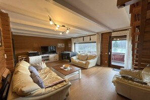 Uma sala de estar acolhedora com sofá, mesa de centro, televisão e lareira.