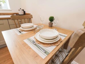 A dining table set with plates, cutlery, and a small potted plant. - Tawny Cottage (Scarborough)