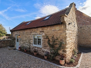 A stone cottage with a red-tiled roof, a small porch, and potted plants. - Tawny Cottage (Scarborough)