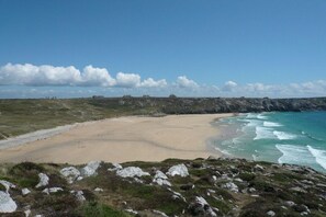 A coastal landscape with a sandy beach, rocky outcrops, and a clear sky. - Lambezen-maison aux volets bleus (Camaret sur mer)