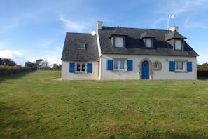 A two-story house with a stone entrance, a blue door, and a small attached garage. - Lambezen-maison aux volets bleus (Camaret sur mer)