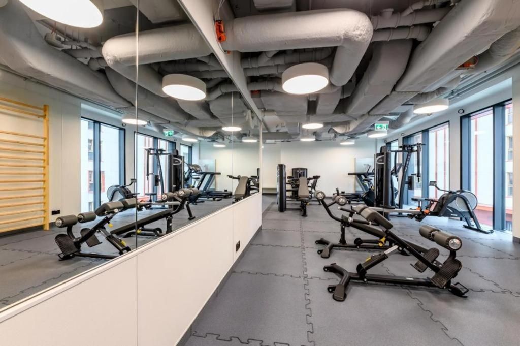 A gym with exercise equipment, large windows, and a mirrored wall.