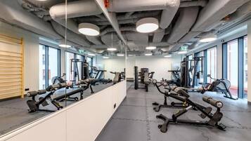 A gym with exercise equipment, large windows, and a mirrored wall.