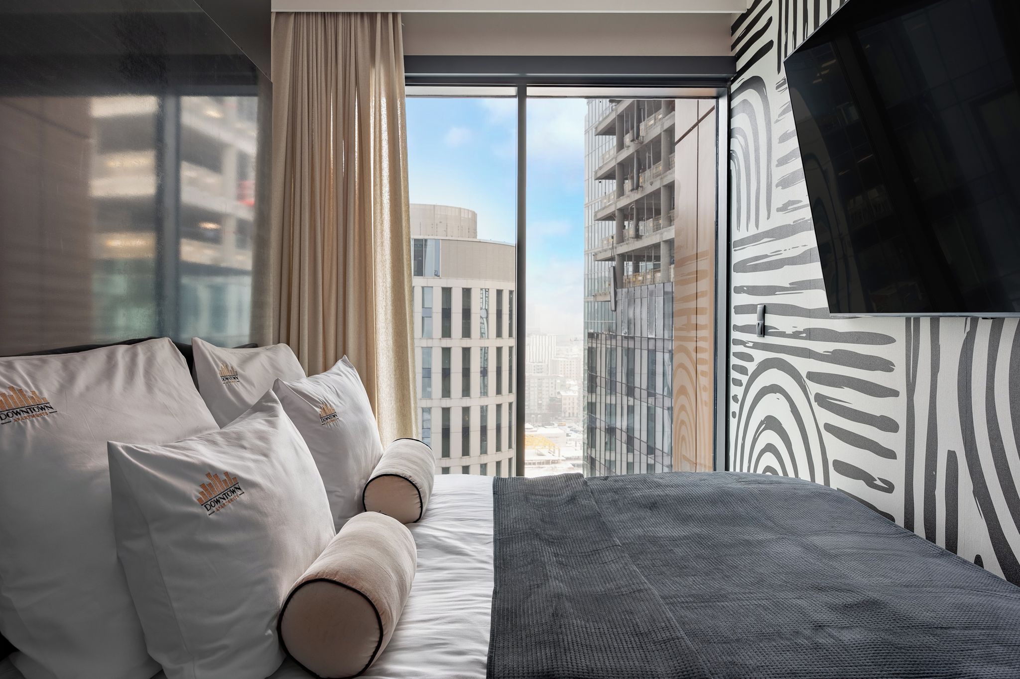 Een moderne hotelkamer met een groot bed, een televisie en uitzicht op de stad.
