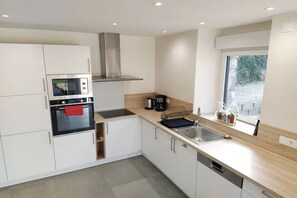Een moderne keuken met inbouwapparatuur, een raam en uitzicht op groen.