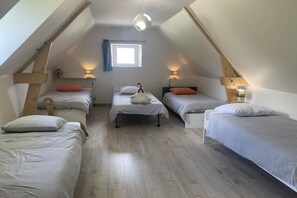 A dormitory room with three beds, a window, and a sloped ceiling. - Holiday home with 1 bedroom (Les Moitiers-d'Allonne)