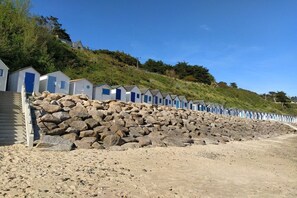 Een rij strandhutten met een stenen muur op de voorgrond.
