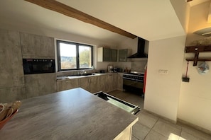 A kitchen with a built-in oven, a window, and a wooden ceiling beam. - Holiday home with 3 bedrooms (Cabrials (Aumelas))