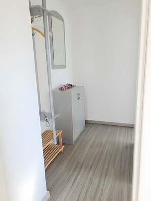 Una habitación minimalista con un armario gris, un banco de madera y un espejo en la pared.