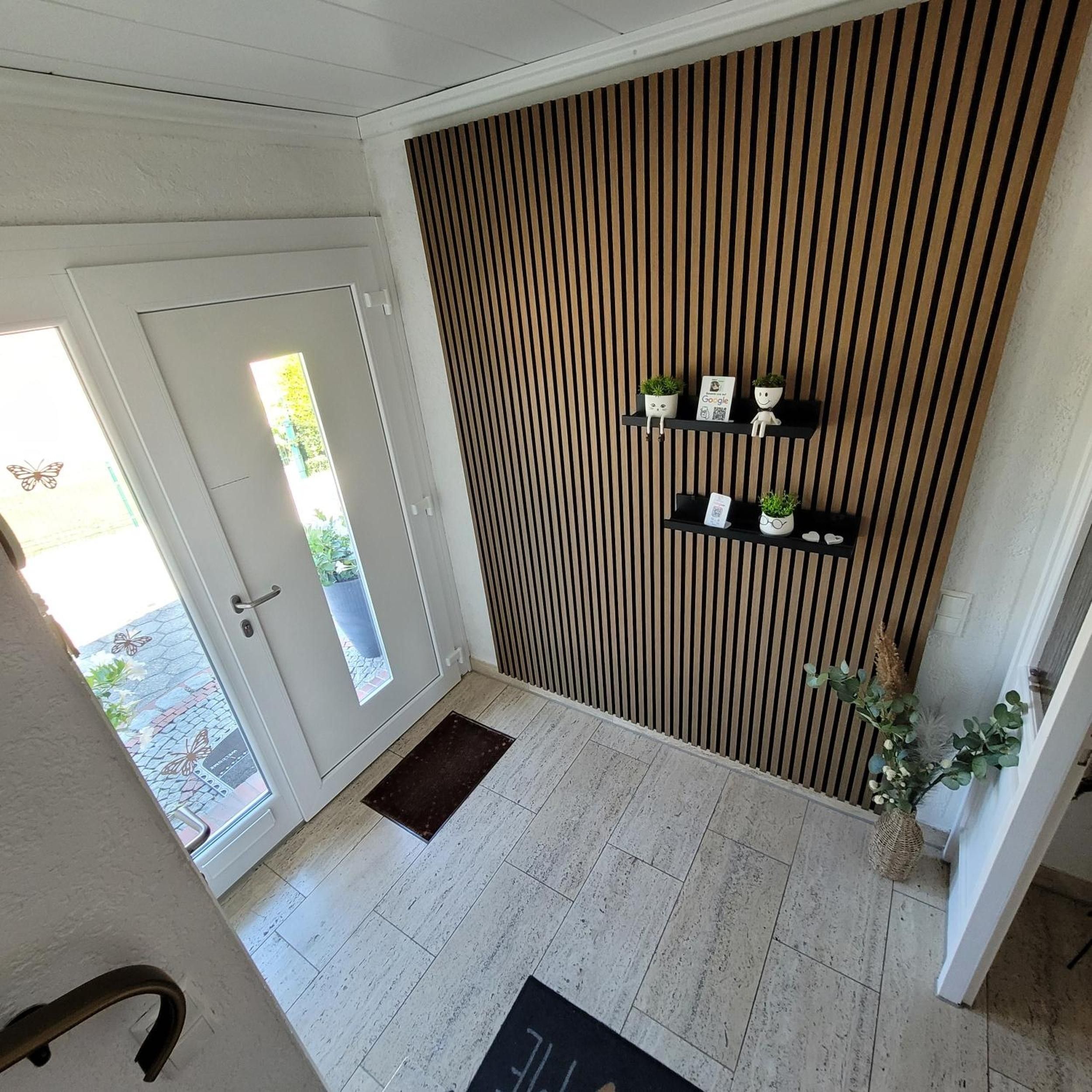 A modern interior with a wooden slat wall, a glass door leading outside, and a small indoor garden on the wall.