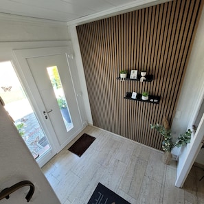 A modern interior with a wooden slat wall, a glass door leading outside, and a small indoor garden on the wall. - Ferienwohnung 'Nordseeperle Strandkorb Am Strand' mit Balkon und WLAN (Wangerland)