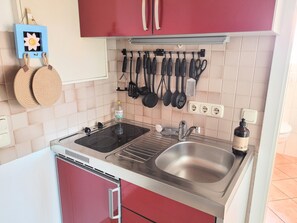 Cuina compacta amb un doble safareig, una placa de cocció i una barra penjant per a les eines de cuina.