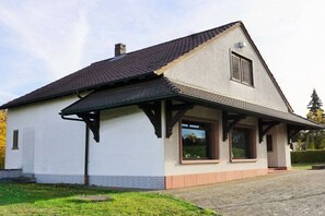 Ein eingeschossiges Haus mit Satteldach, einem Schornstein und einer kleinen Veranda.