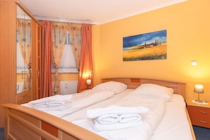 Ein Hotelzimmer mit Doppelbett, einem Nachttisch mit Lampe, einem Bild an der Wand und einem Fenster mit Vorhängen.