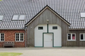 Un edificio con tetto in tegole, facciata in legno e una porta centrale con cornice verde.