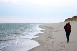 A person walking along a sandy beach with the ocean in the background. - Sonnenhof by the sea (Osterhever)