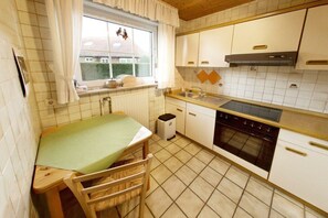 A compact kitchen with a window, a sink, a stove, and a small trash bin. - Holiday home in Hooksiel with swimming pool (Hooksiel)