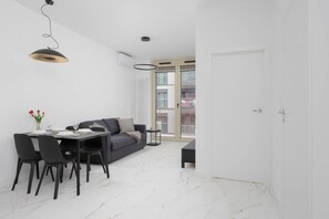 Een moderne eethoek met een zwarte tafel, witte stoelen en een grijze bank.