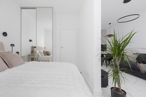 Een moderne slaapkamer met een bed, nachtkastje, lamp en een potplant.