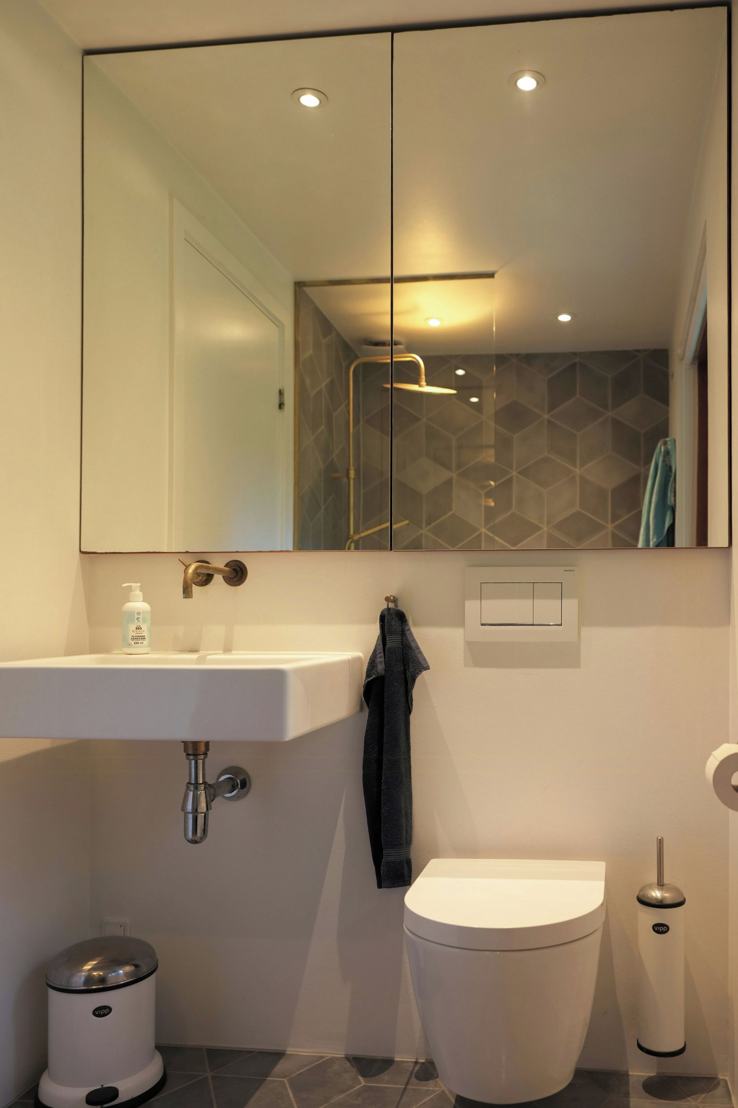Une salle de bain moderne avec un lavabo blanc, des toilettes, un bidet et une poubelle.