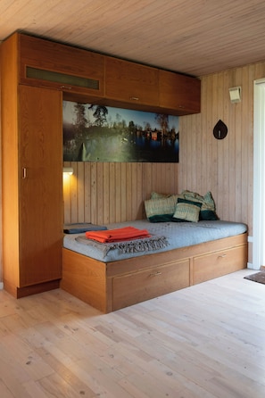 Una habitación con cama empotrada, paredes de madera y un amplio ventanal con vistas al paisaje.