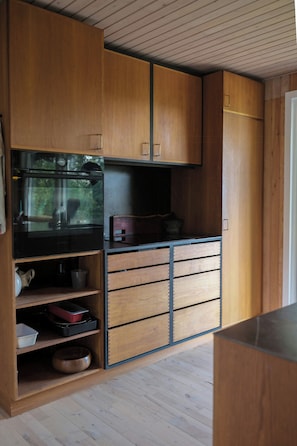 Une cuisine compacte avec des meubles en bois, un four encastré et une machine à café.