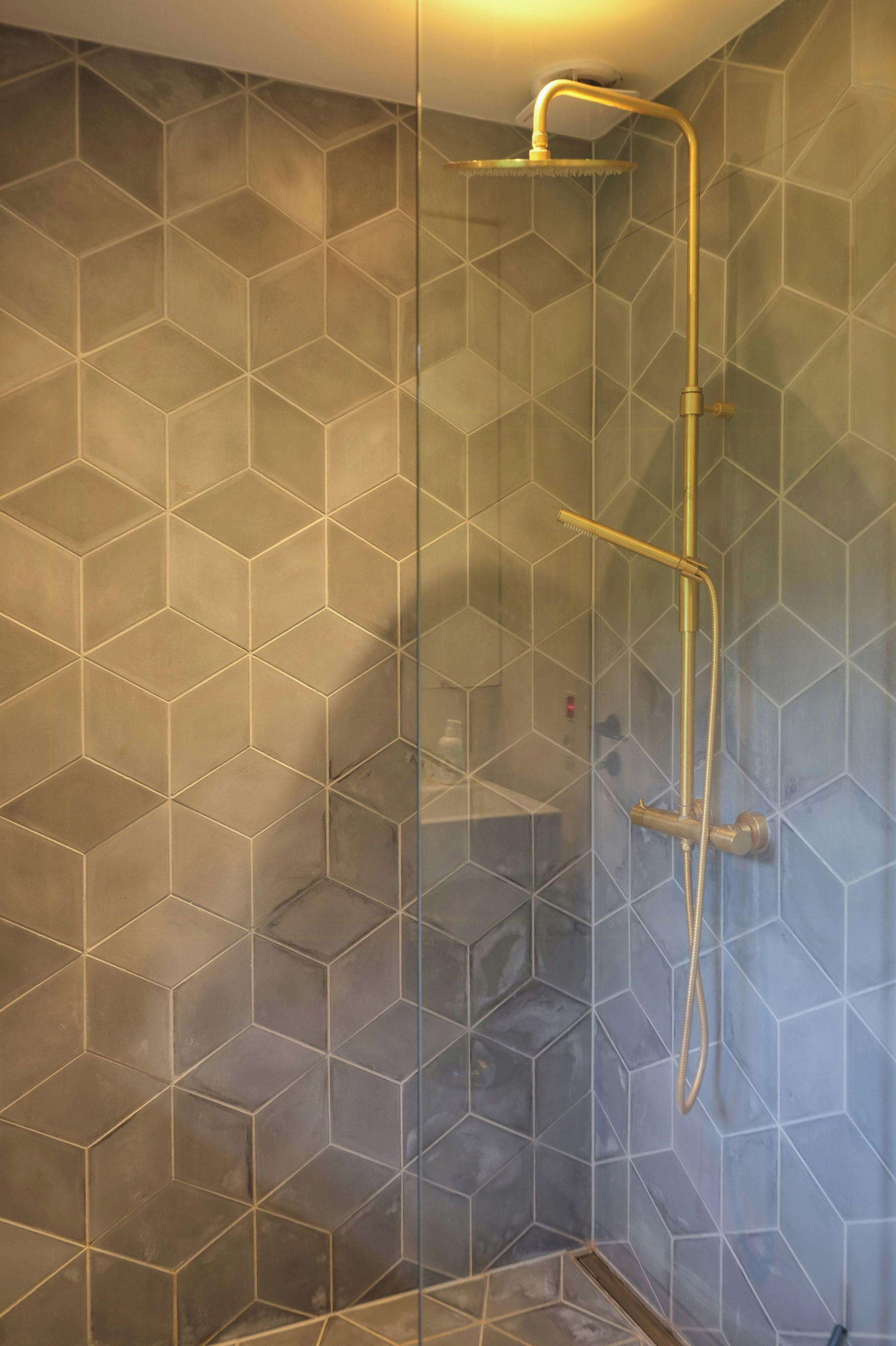 Une douche dont les murs sont recouverts de carreaux aux motifs géométriques.