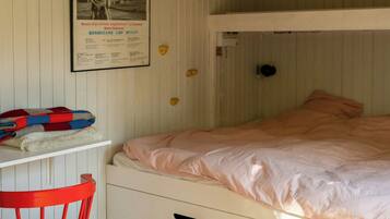 Ein Schlafraum mit Etagenbett, Holzboden, einem roten Stuhl und einem Poster an der Wand.