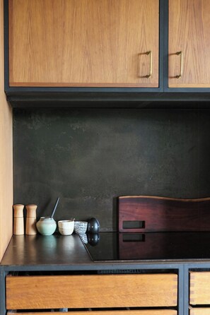 Una cocina con armarios de madera, encimera negra y una silla de madera.