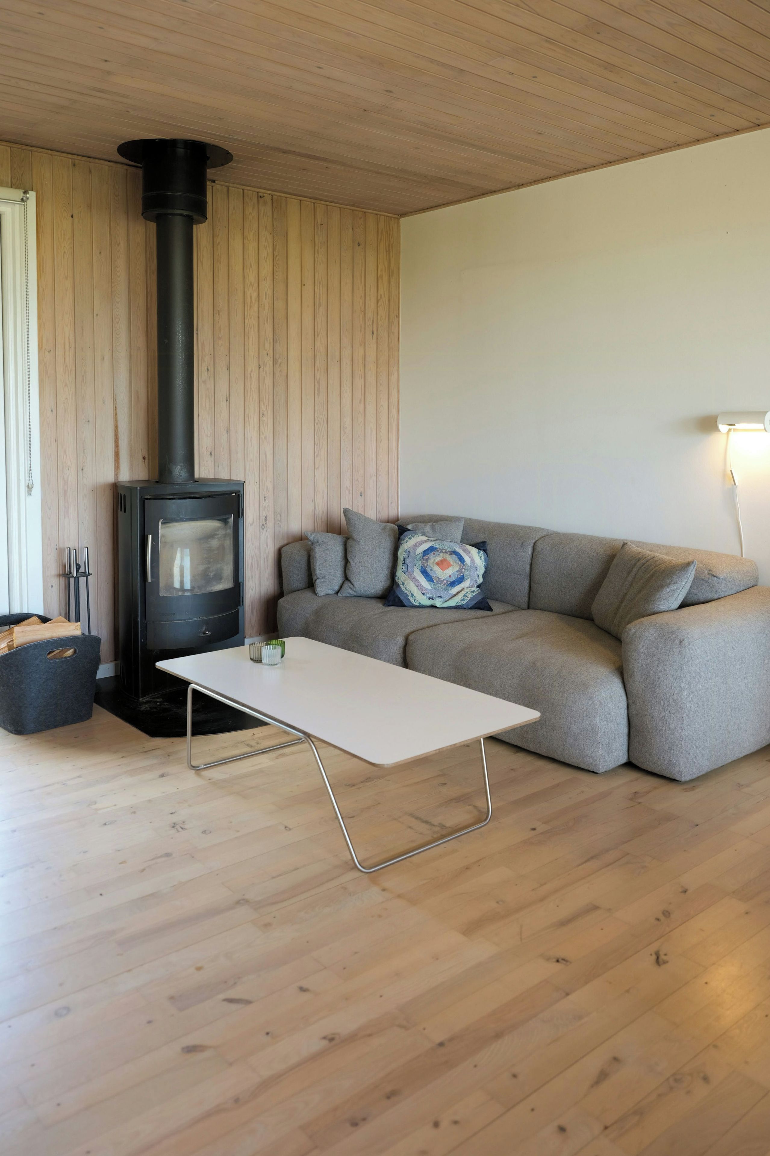 Una sala de estar moderna con una estufa de leña, un sofá gris y una mesa de centro blanca.