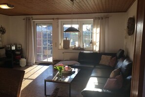 Un salon avec un canapé, une table basse, une cheminée et une fenêtre avec des rideaux.