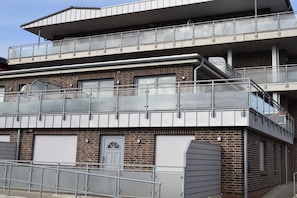 A multi-story building with a flat roof, balconies, and a brick facade. - Holiday apartment in Büsum with swimming pool (Büsum)