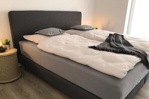 A bed with a dark headboard, white bedding, and a black throw blanket. - Holiday apartment in Büsum with swimming pool (Büsum)