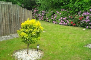 A well-maintained garden with a small tree, a wooden fence, and a variety of flowering plants. - Holiday apartment with 1 bedroom (Cuxhaven)