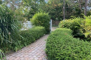 A paved pathway surrounded by dense greenery and a white fence. - Holiday home Mechelsdorf (Mechelsdorf)
