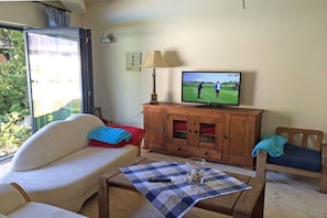 A living room with a sofa, a television, a wooden cabinet, and a table with a checkered tablecloth. - Holiday home Mechelsdorf (Mechelsdorf)