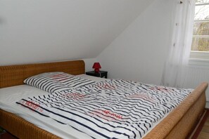 A single bed with a striped bedspread, a red lamp on a bedside table, and a window with curtains. - Holiday home Mechelsdorf (Mechelsdorf)