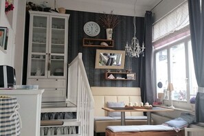 A cozy room with a white staircase, a bench, a table with candles, and a window with curtains. - Holiday apartment with 1 bedroom (Norderney)