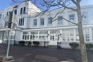 A white building with multiple windows and a black fence in front. - Holiday apartment with 1 bedroom (Norderney)